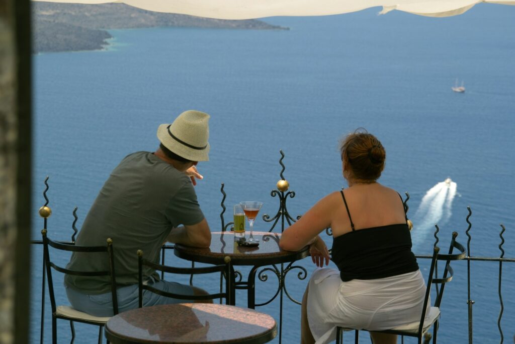 back view of man and woman sitting in front of terrace with sea view